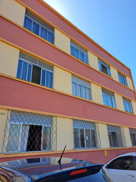 un edificio con ventanas y un coche aparcado delante en Ap da Lú en Teresópolis