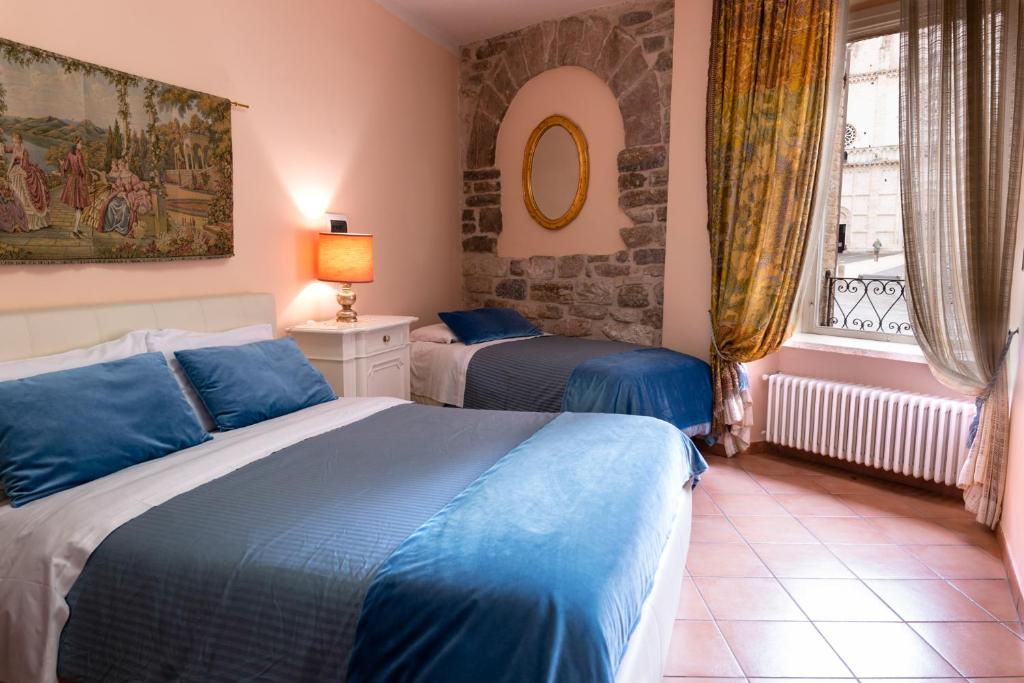 アッシジにあるApartment Assisi Cattedraleのベッドルーム1室(ベッド2台、窓付)