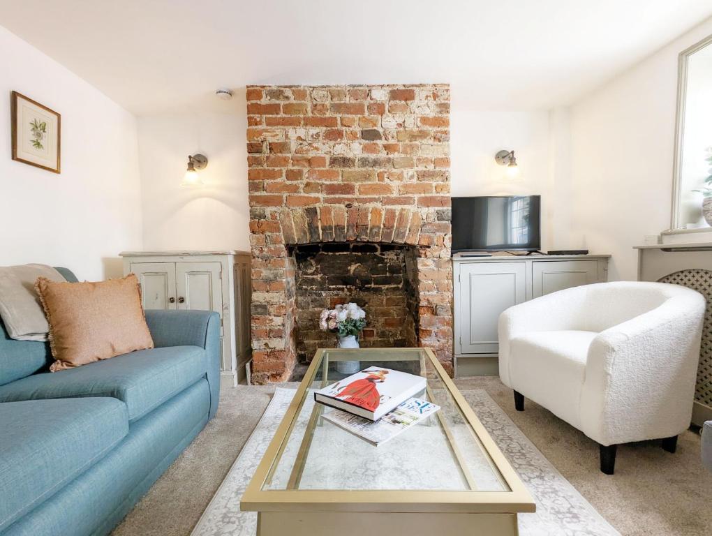 a living room with a blue couch and a brick fireplace at June Cottage in Bognor Regis