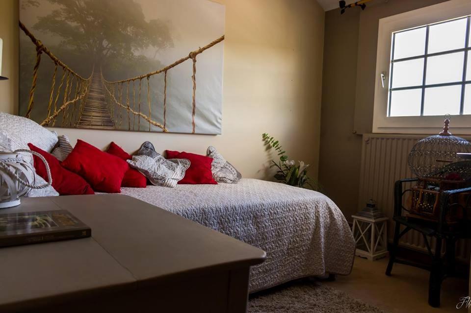 a bedroom with a bed with red pillows and a window at La maison d'Huguette in Profondeville