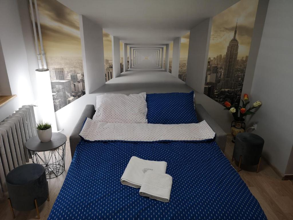 a bedroom with a blue bed with a view of a city at Apartament przy dworcu in Krosno