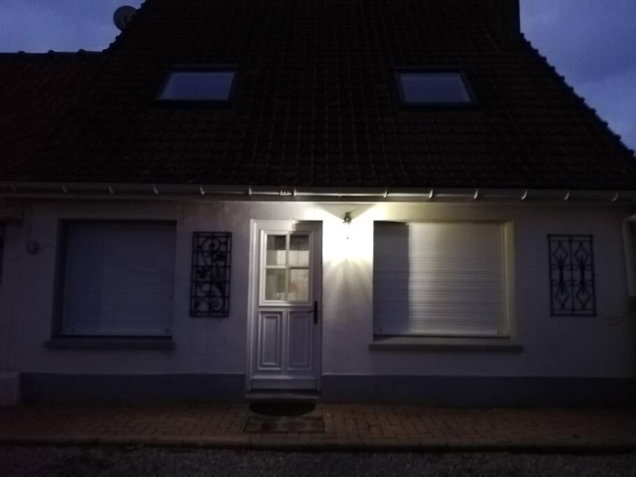 a white house with a door at night at La petite maison de Marie in Licques