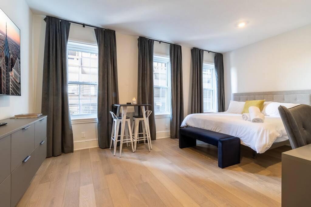 a bedroom with a bed and a desk and windows at Thena Hotel - Large Studio in Philadelphia