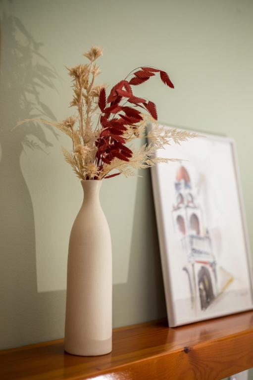 a white vase with flowers on a table next to a picture at Margaritas apartments in Symi