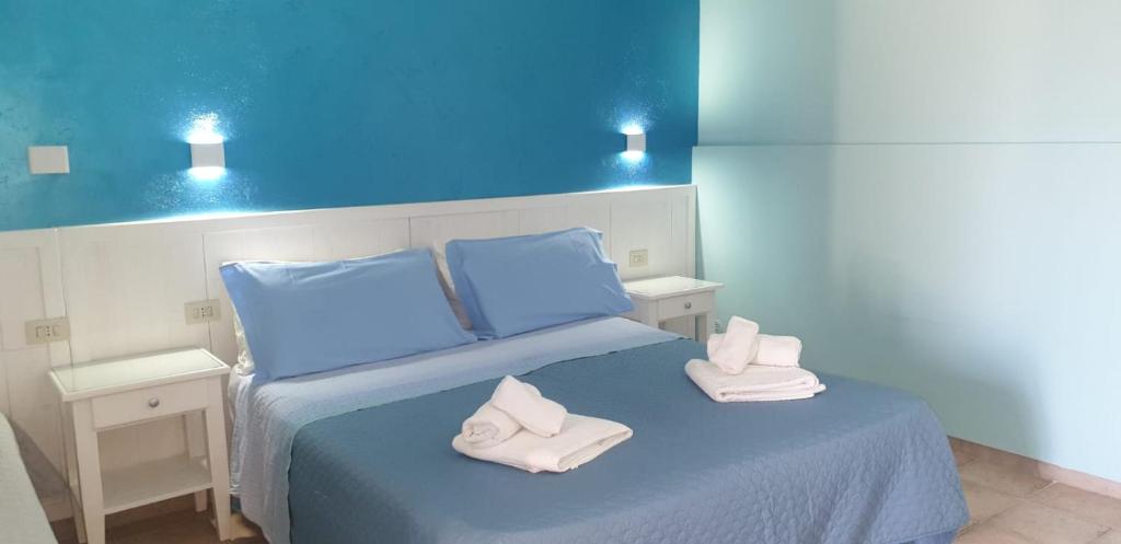 um quarto azul com uma cama com toalhas em La Carcara em Otranto