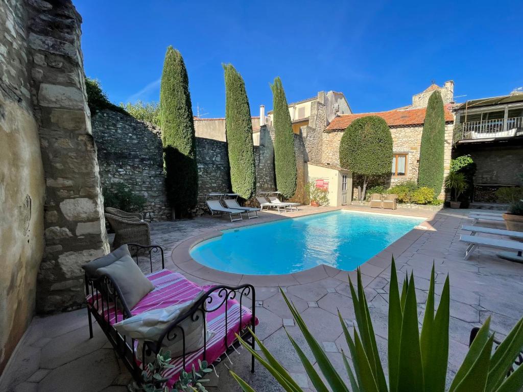 einen Pool in einem Garten mit Stühlen und einem Gebäude in der Unterkunft Villa Velleron in Velleron