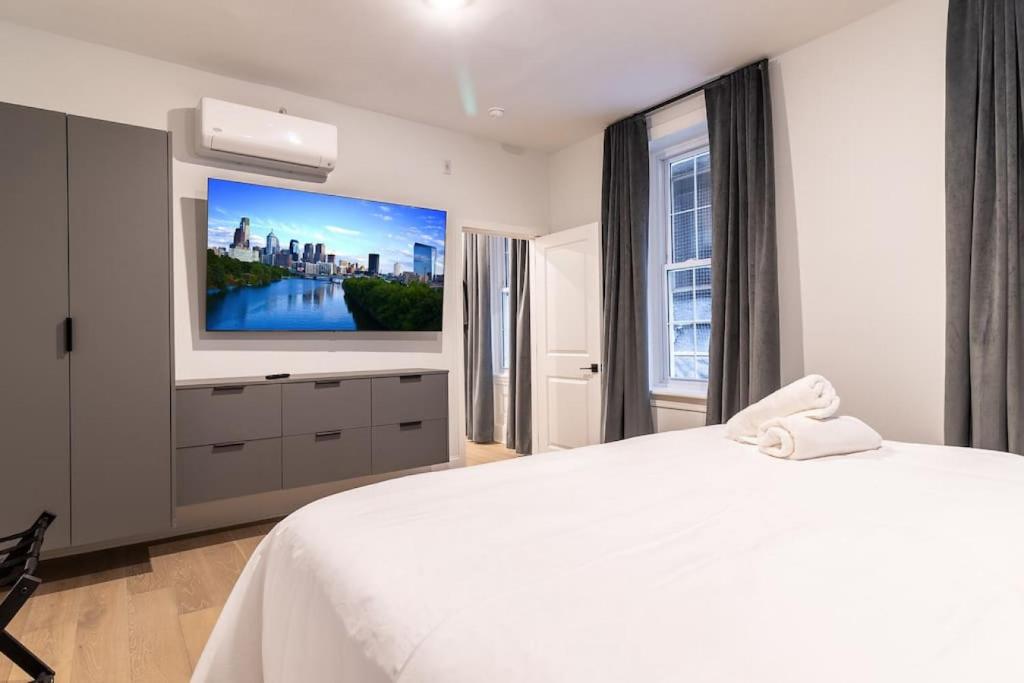 um quarto com uma cama branca e uma televisão de ecrã plano em Thena Hotel - Beautiful 1 Bedroom em Filadélfia