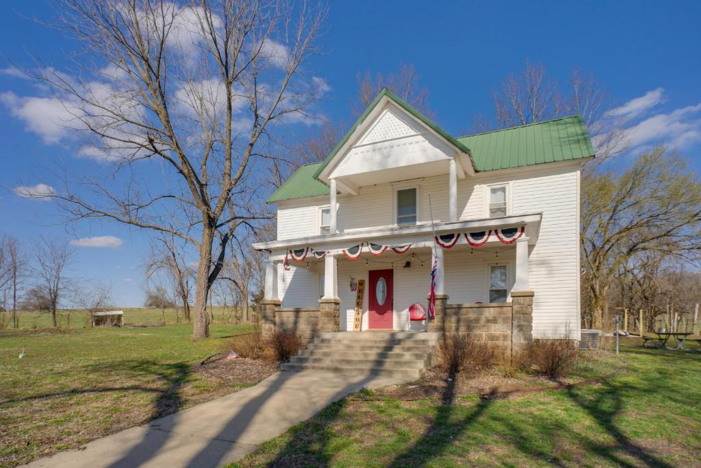 Greenfield的住宿－Spacious Missouri Vacation Rental with Fire Pit!，白色的房子,有绿色的屋顶和红色的门