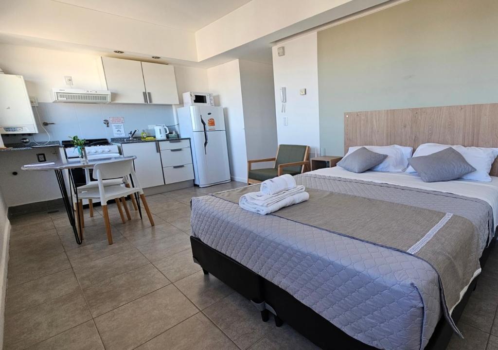 1 dormitorio con 2 camas y cocina con mesa en Infinito - Departamento con vista al mar en Comodoro Rivadavia
