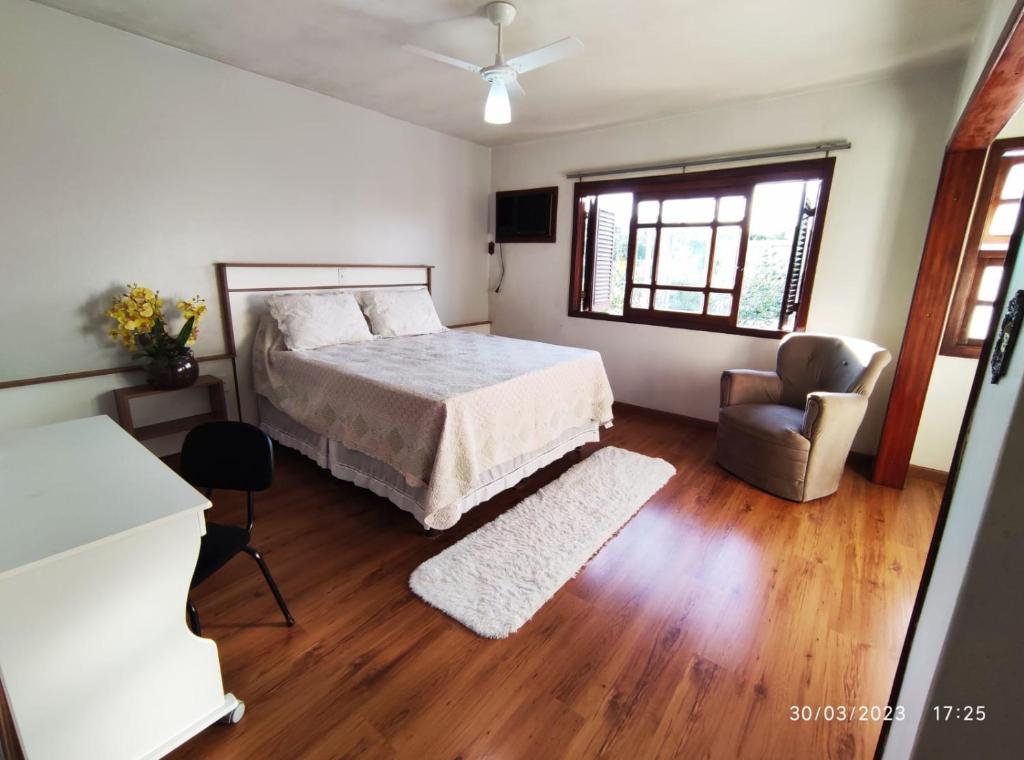 a bedroom with a bed and a chair and a window at Pousada com vista para o Cristo 3 in Encantado