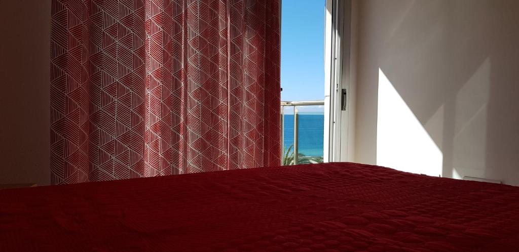 een slaapkamer met een rood bed en een raam bij Apartamento Arguineguín centro, vistas al mar in La Playa de Arguineguín