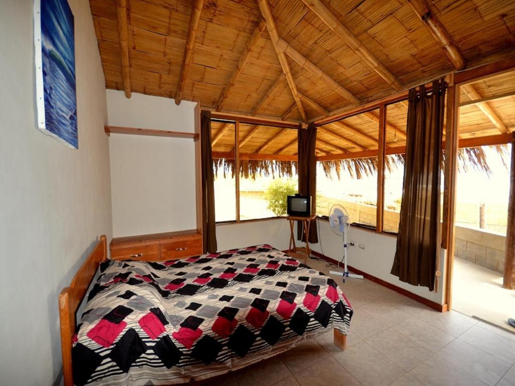 ein Schlafzimmer mit einem Bett in einem Zimmer mit Fenstern in der Unterkunft Wayra in Lobitos