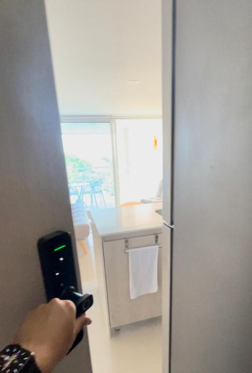 a person holding a cell phone in front of a refrigerator at Infinity Blue - Playa Dormida in Santa Marta