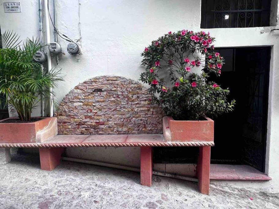 um banco sentado em frente a um edifício com flores em Habitación independiente a unos pasos del centro em Taxco de Alarcón