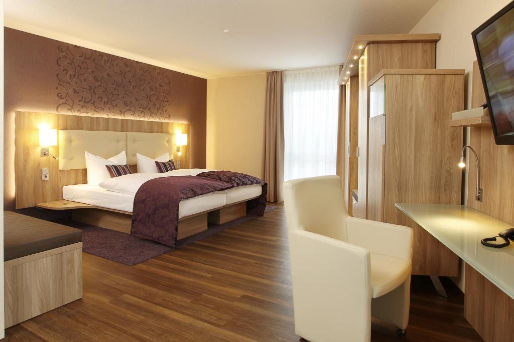 a hotel room with a bed and a flat screen tv at Hotel Simonshof in Wolfsburg