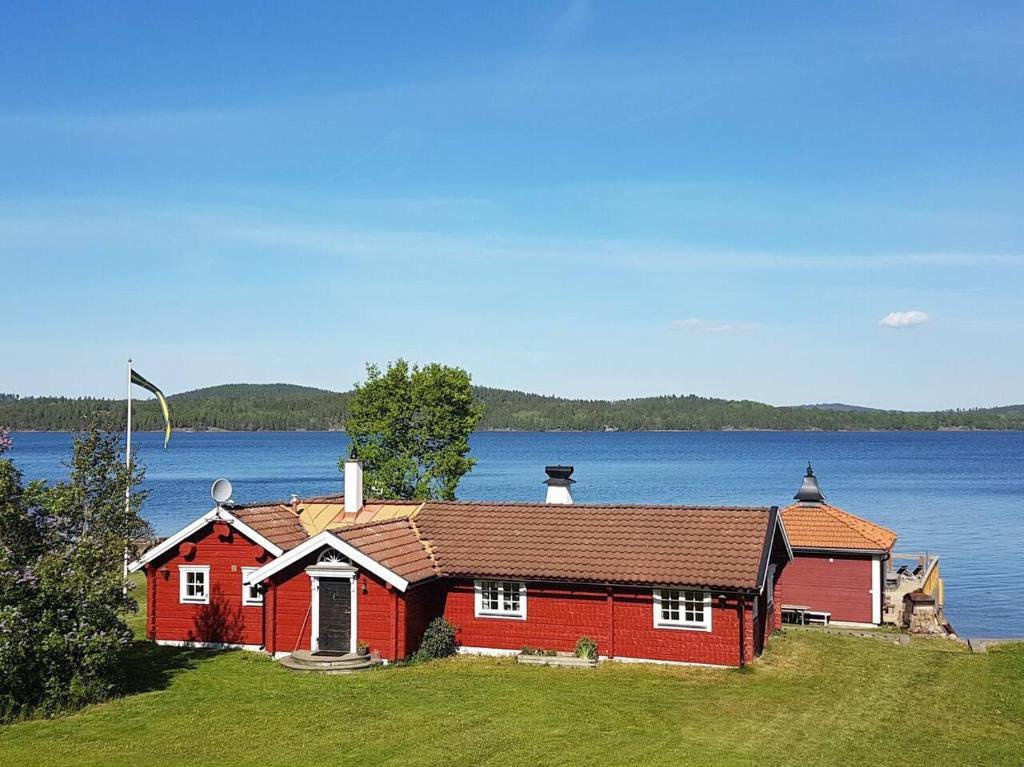 a red house on the side of a lake at Cottage with spa sauna boat as extra cost in Hult