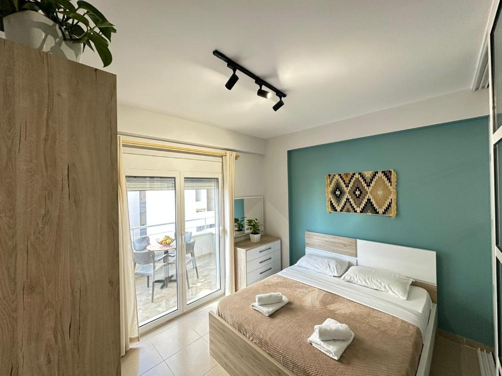 een slaapkamer met een bed met een blauwe muur bij TreA Accomodations - On Private Beach with sunbed & umbrella in Vlorë