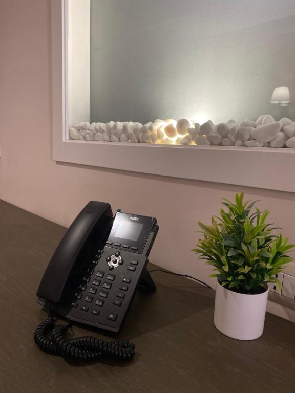 a black phone sitting on a desk with a plant at Doanesia Premium Hotel & Spa in Tirana