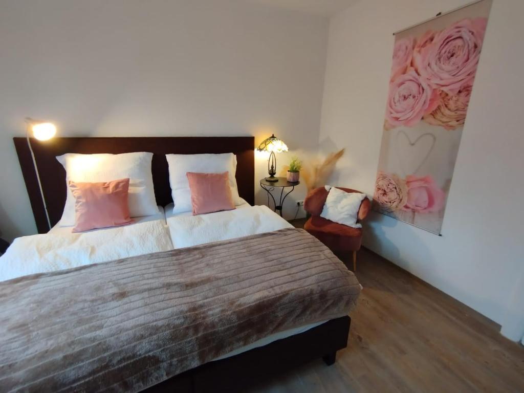 ein Schlafzimmer mit einem großen Bett mit rosa Kissen in der Unterkunft Ferienwohnung Fuchsbau Jüterbog in Jüterbog