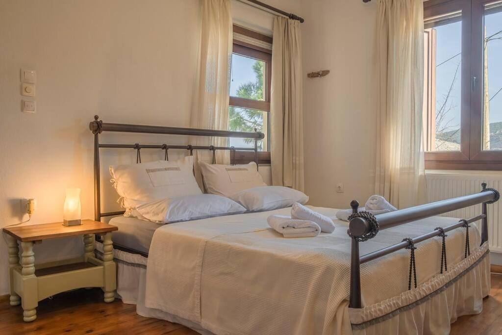 a bedroom with a bed and a table and a window at Odysseas Pelion House in Kalamaki