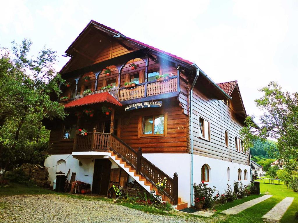 バドゥ・イゼイにあるPensiunea Ardeleanのバルコニーと階段が備わる大きな木造家屋です。