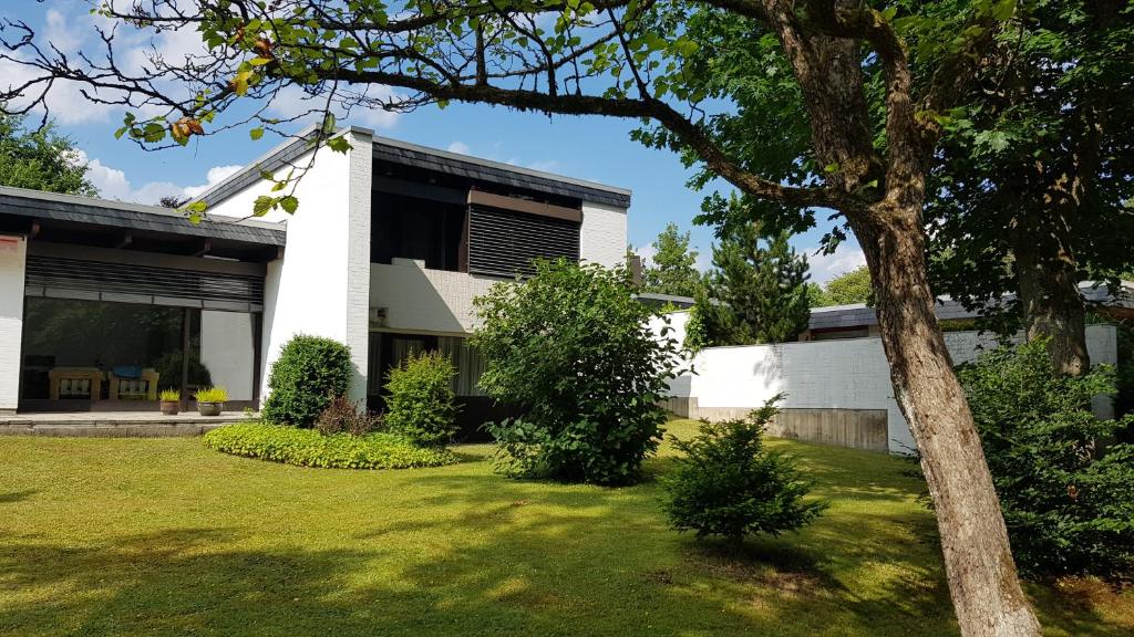 una casa blanca con un árbol en el patio en Exklusive Ferienwohnung Hattorfer Teiche en Wolfsburg