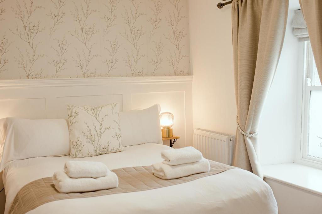 a bedroom with a bed with two towels on it at JT Abergwaun hotel in Fishguard