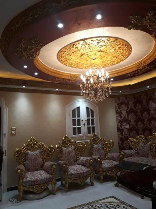 Rental apartment at Ras El Bar City في ‘Izbat al Jirabī: غرفة فيها كراسي وثريا وسقف