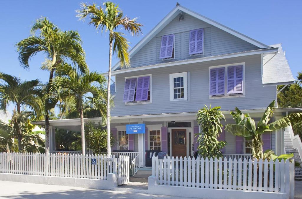 una cerca blanca frente a una casa con palmeras en The Inn on Fleming, en Key West