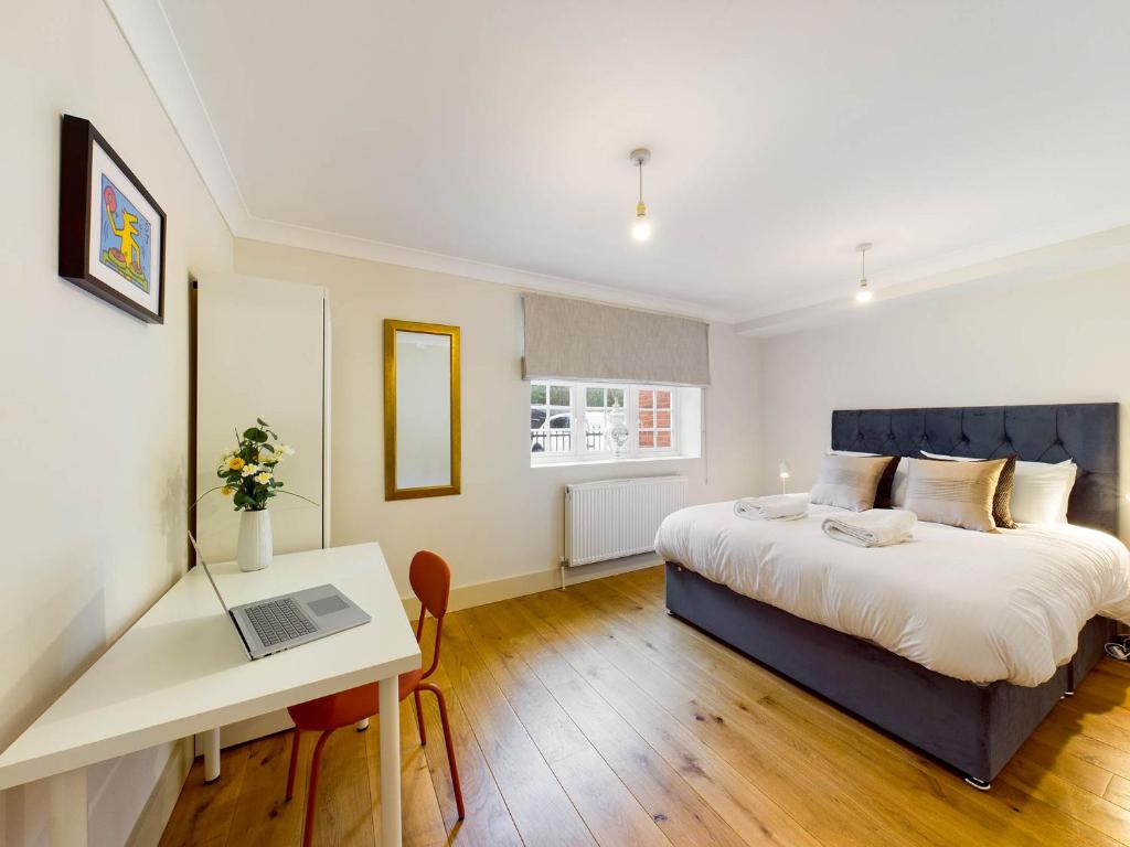 a bedroom with a bed and a desk with a laptop at Redhill town centre apartments by Livingo in Redhill