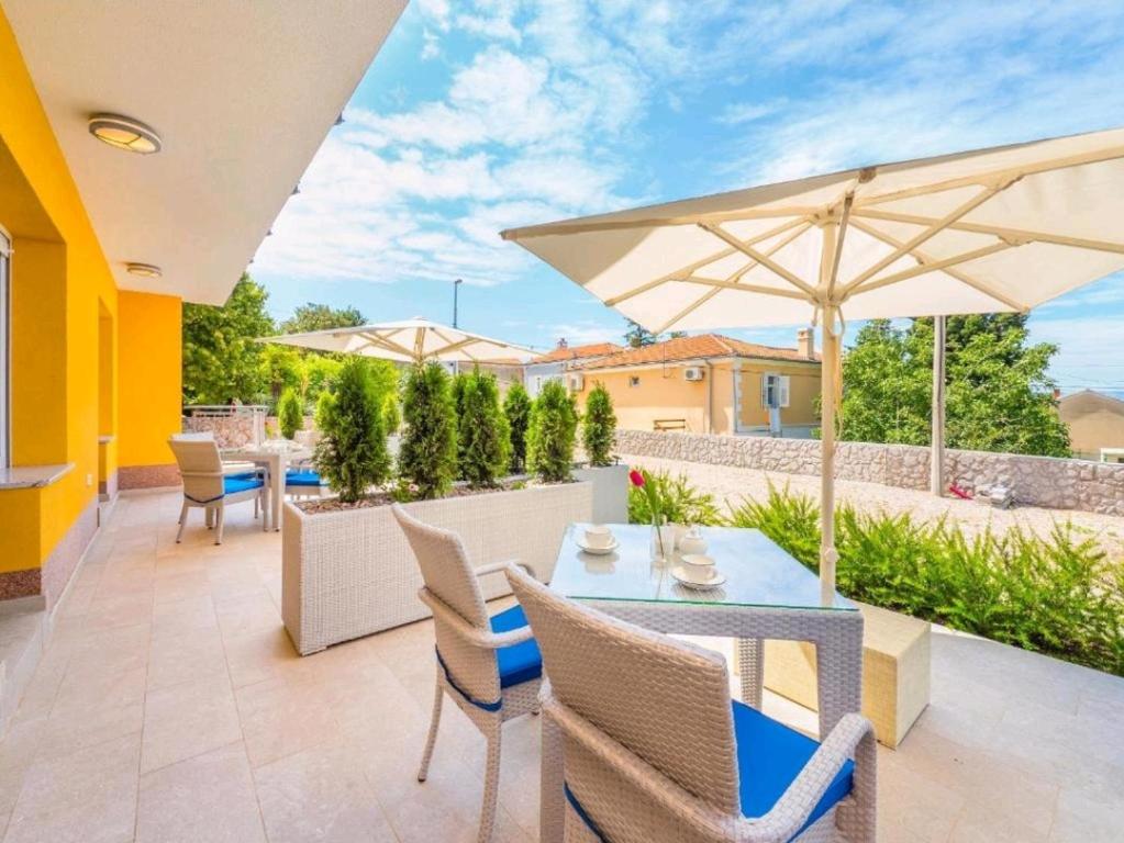 eine Terrasse mit einem Tisch, Stühlen und einem Sonnenschirm in der Unterkunft Adriatico in Omišalj