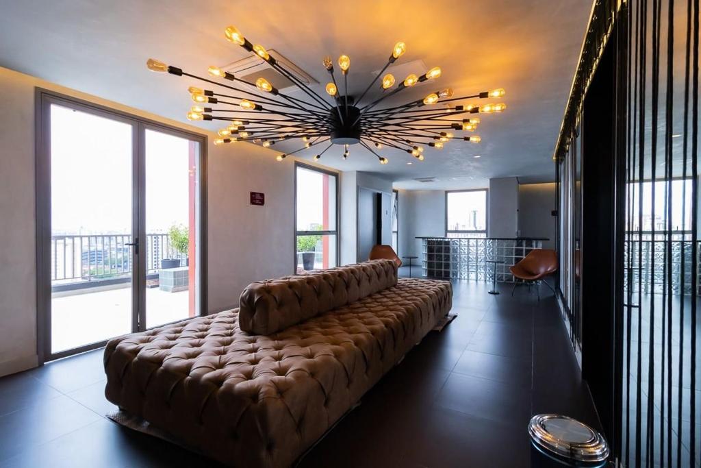 un grande divano in una stanza con un grande lampadario a braccio di Studios Novíssimos com Piscina no Rooftop e vista para o Allianz Parque a San Paolo