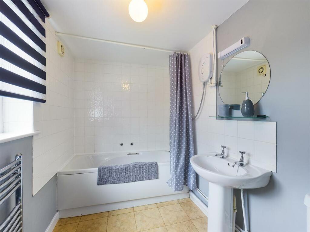 a white bathroom with a tub and a sink at The Coach House at Copper Hall in Leominster