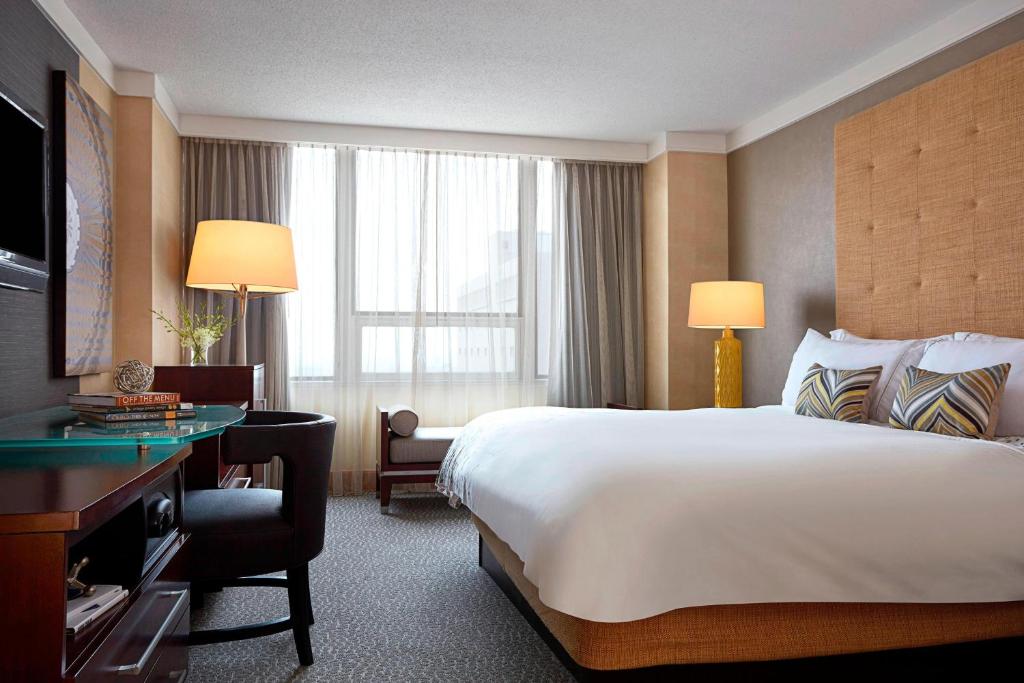 コロンバスにあるRenaissance Columbus Downtown Hotelの大きなベッドとデスクが備わるホテルルームです。