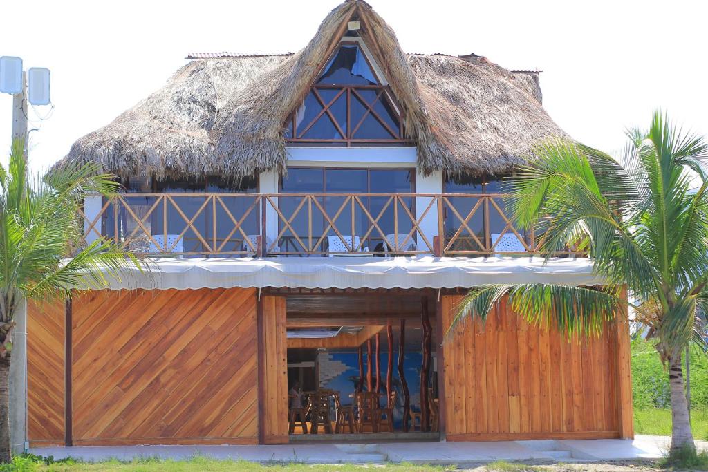 dom z dachem krytym strzechą i palmami w obiekcie Cabaña Yalis SAS w mieście Cartagena de Indias