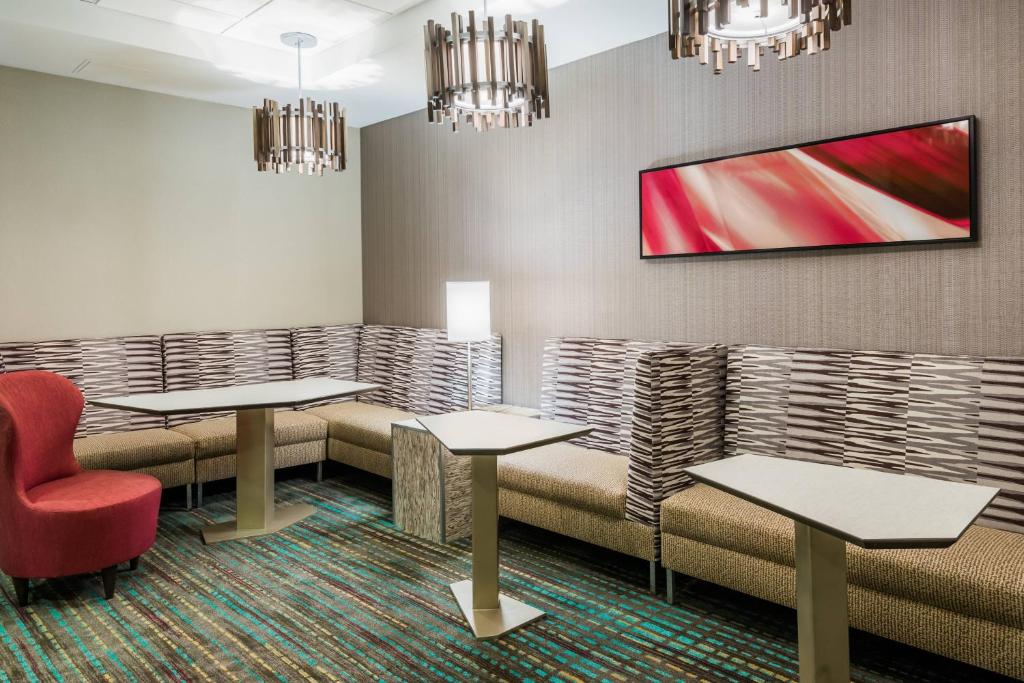 a waiting room with tables and a tv on the wall at Residence Inn Charlotte SouthPark in Charlotte
