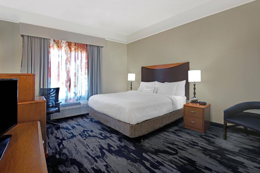 a hotel room with a bed and a chair at Fairfield Inn and Suites Carlsbad in Carlsbad