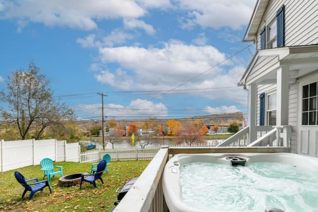 un patio trasero con bañera de hidromasaje y sillas en River Front Home In the Heart of Ithaca, en Ithaca