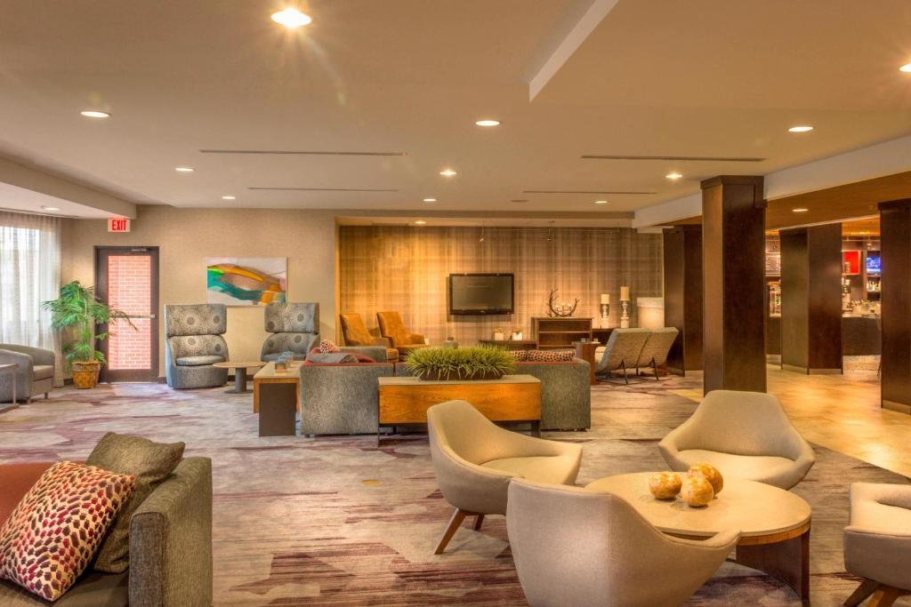 格林斯伯勒的住宿－格林斯博羅機場萬怡酒店，大堂配有沙发、椅子和电视。