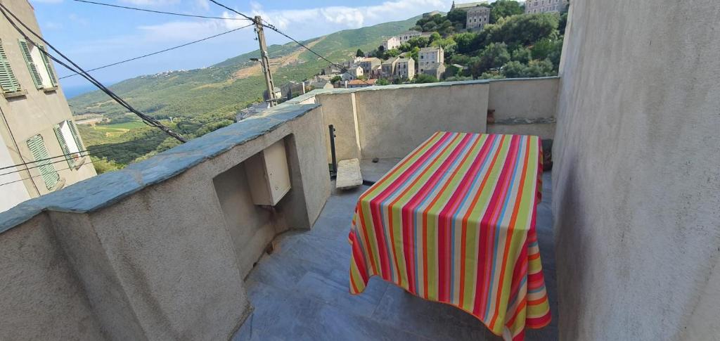 a table with a striped table cloth sitting on a balcony at maison de village rogliano / macinaggio cap corse in Rogliano