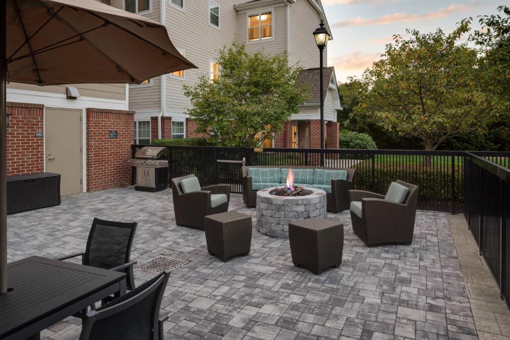 a patio with a fire pit and chairs and an umbrella at Residence Inn Milford in Milford