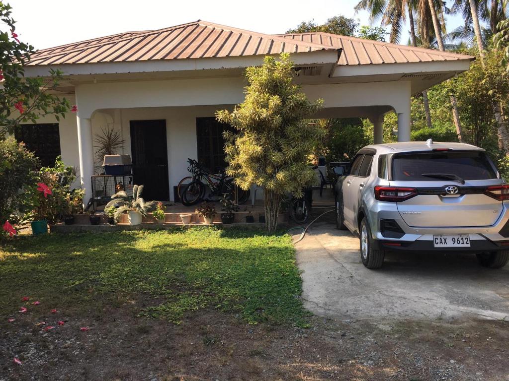a white suv parked in front of a house at Riverside Transient House/Balingasay-Patar Beach in Balingasay
