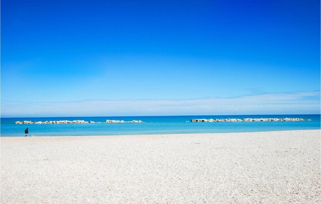 a person walking on a sandy beach near the ocean at Gorgeous Apartment In Fano With Wifi in Fano
