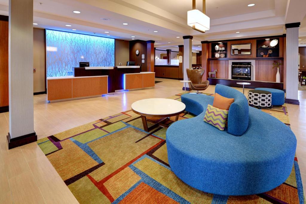 a hotel lobby with a blue chair and a table at Fairfield Inn & Suites by Marriott Wausau in Weston