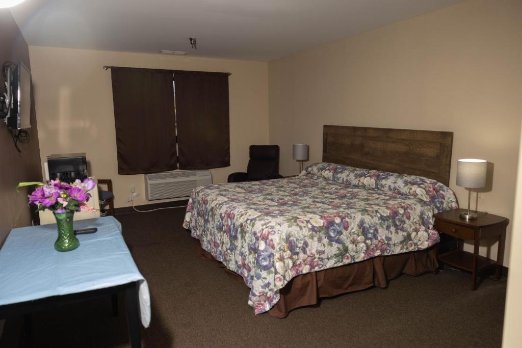 een hotelkamer met een bed en een tafel met bloemen bij Lafayette Inn in Moundsville