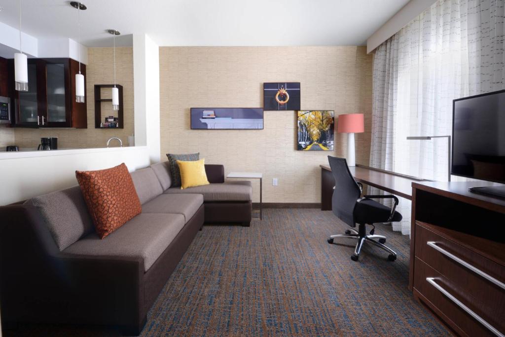 a hotel room with a couch and a desk and a television at Residence Inn by Marriott Houston Pasadena in Pasadena