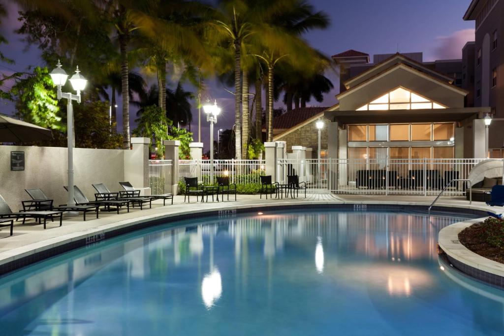 a swimming pool at night with chairs and a house at Residence Inn by Marriott Fort Lauderdale Airport & Cruise Port in Dania Beach