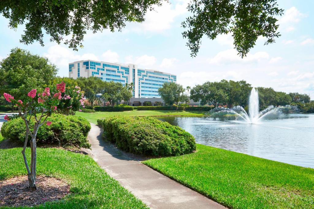 a park with a fountain and a lake and a building at Renaissance Orlando Airport Hotel in Orlando