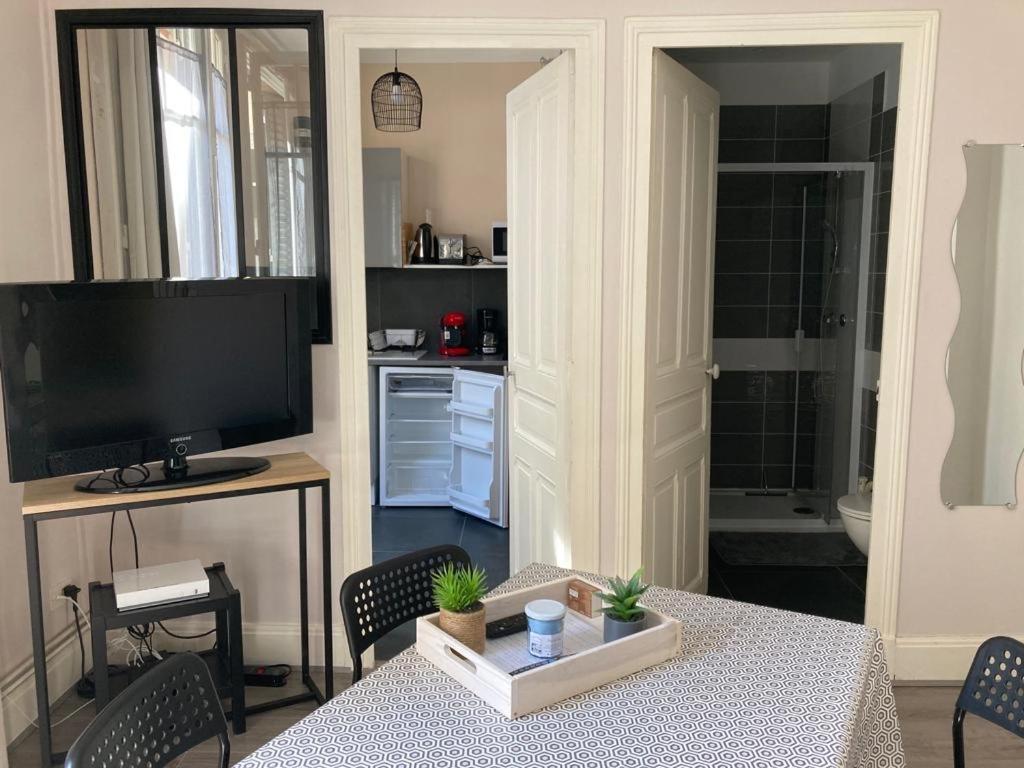 Studio cosy proche parcs, opéra, centre ville في فيشي: غرفة معيشة مع طاولة وتلفزيون