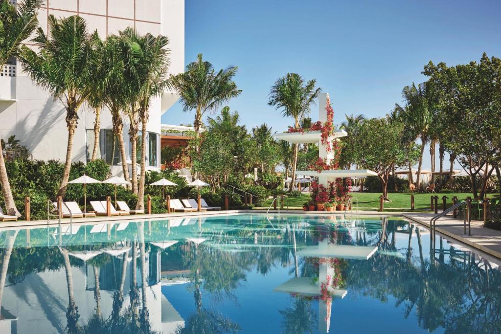 a swimming pool with palm trees and a building at The Miami Beach EDITION in Miami Beach